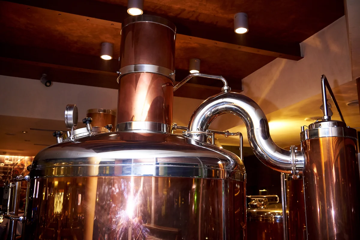 Cuve et colonne en cuivre reliées par un col de cygne en inox dans une distillerie